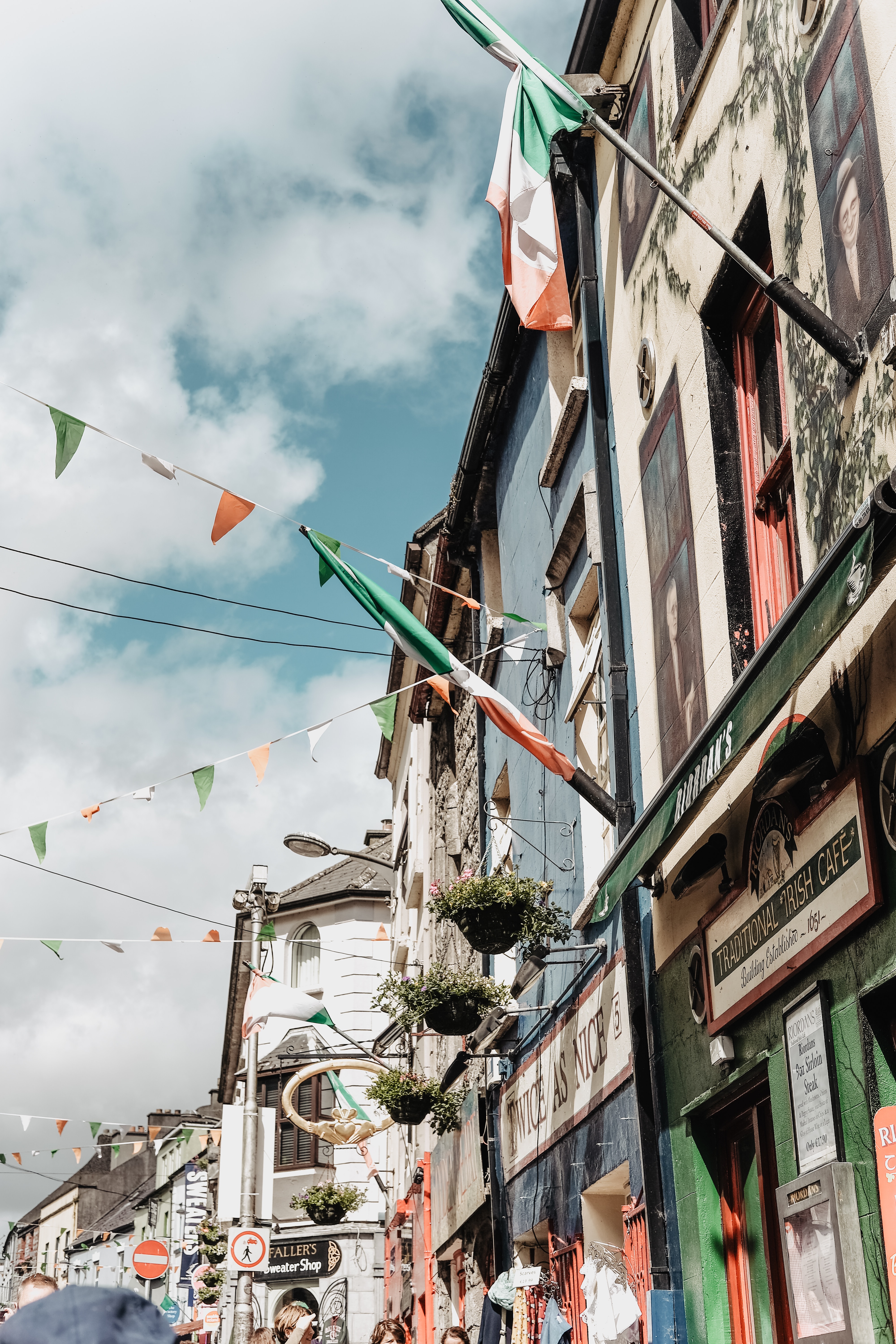 A row of historic buildings with Irish flags hung between them.