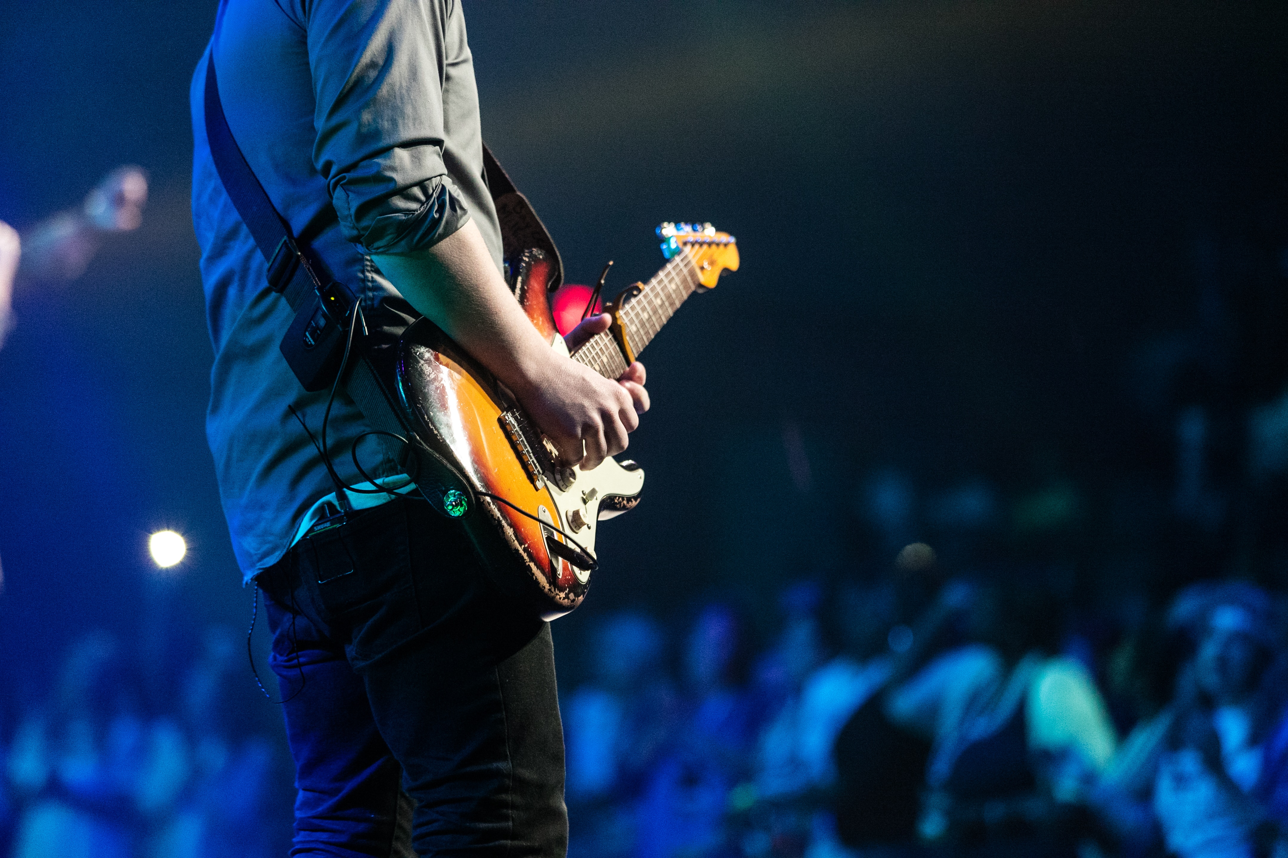 A musician playing the electric guitar in front of a large audience.