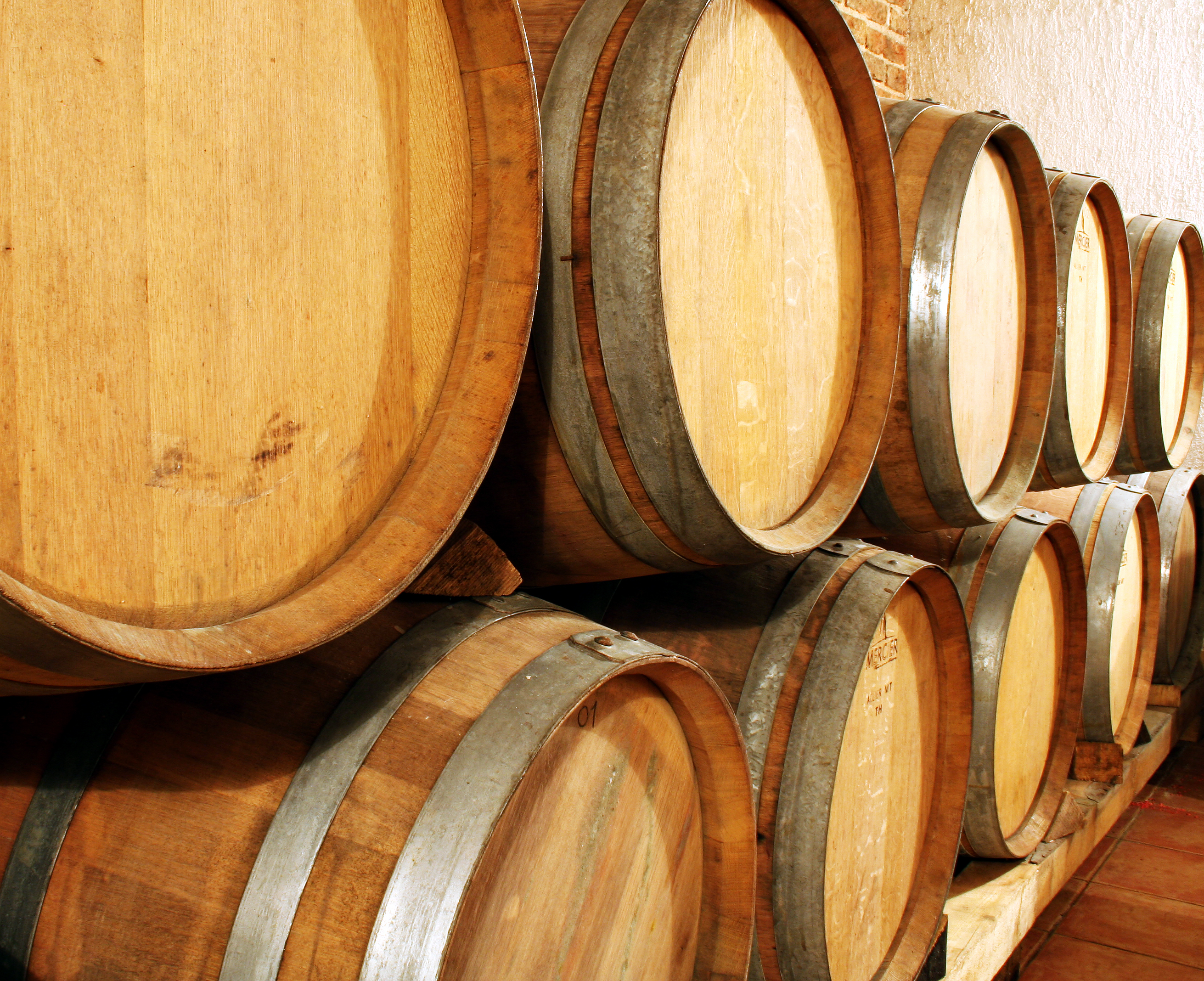 two stacked rows of brown wooden wine barrels with tops of barrels facing viewer